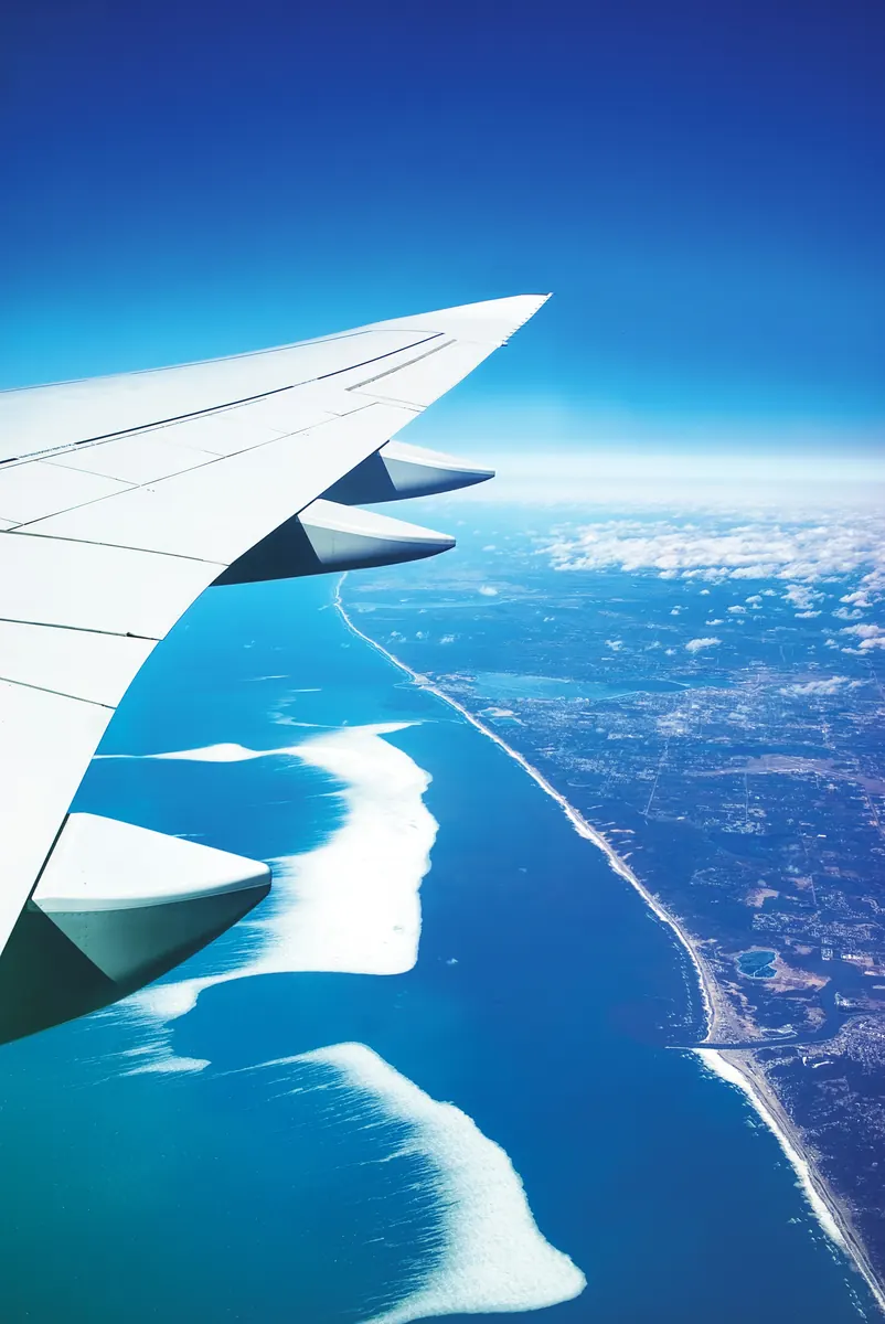 Airliner wing over the coastline, representing mandatory retirement age planning for airline pilots